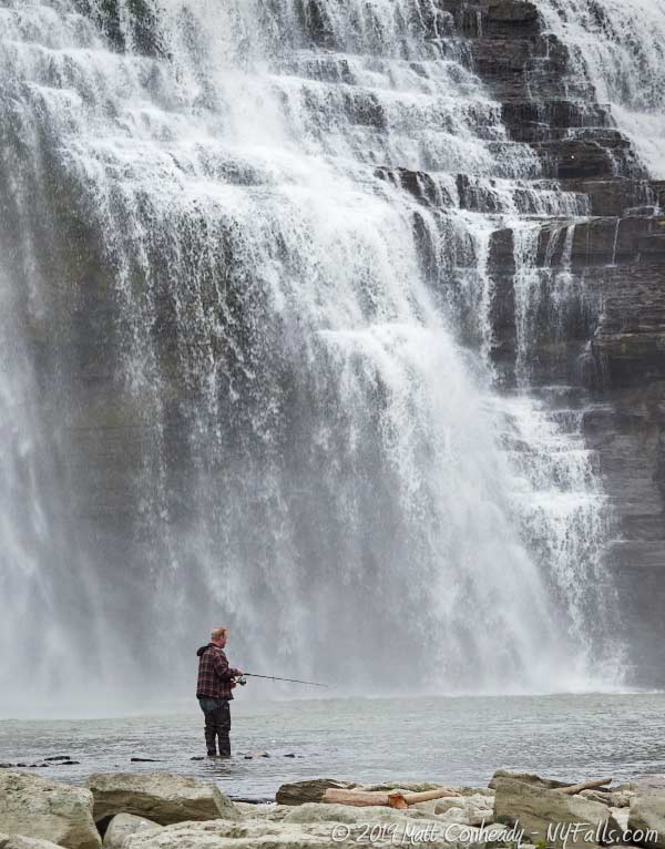 A fisherman standing in the water below Rochester's Lower Falls