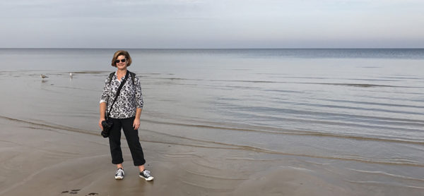 Kelly Lucero stands on the shore of the Baltic Sea in Latvia with her camera