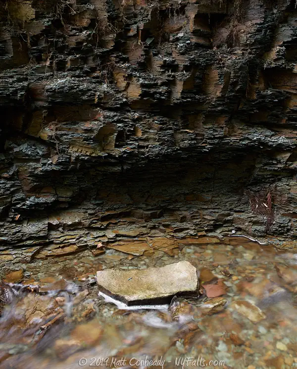 The grayish-brown stones of the gorge wall at Densmore Falls