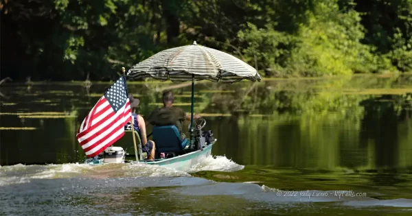 Motor boat with 2 men, a striped umbrella and an American flag