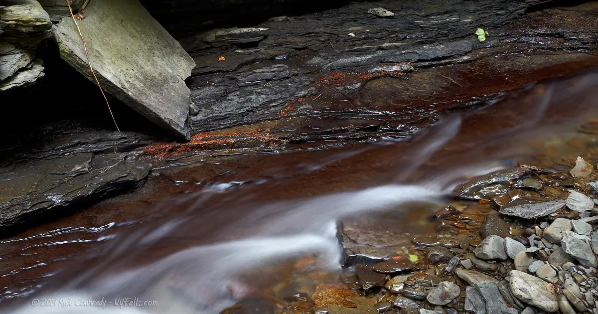 A closeup of Catlin Mill Creek in Deckertown gorge showing a red, iron-stained slick bedrock