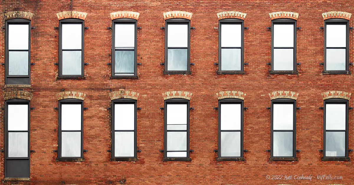 Uniform rows of windows reflecting the sky on a brick factory building in the High Falls district.