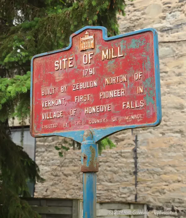 A historic marker next to the falls: Site of Mill - 1791 - Built by Zebulon Norton of Vermont, first pioneer in village of Honeoye Falls