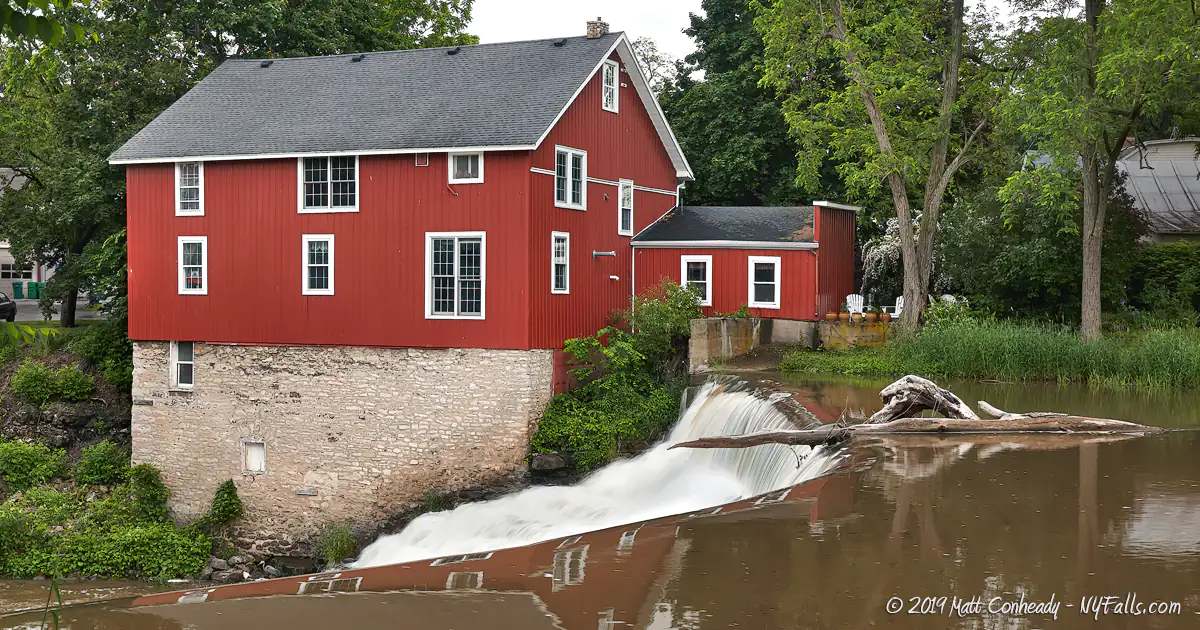 The red mill with the crest of Honeoye Falls and the mill pond in the foreground.