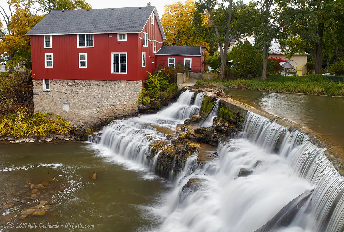A view of Honeoye Falls in low flow when the middle of the falls is bare rock. On the other side of the Red Mill building, which is now a private residence.