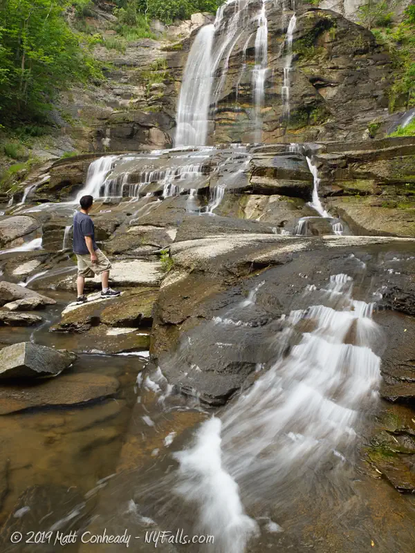 A man stands at the bottom of Montville Falls and looks up.