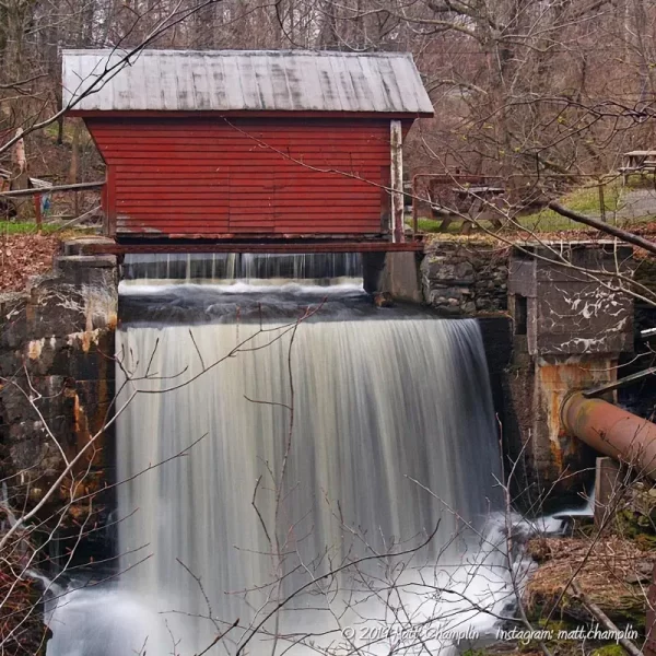 A closeup of the waterfall created by the mill dam on Bear Swamp Creek, and the red covered bridge in front of it.
