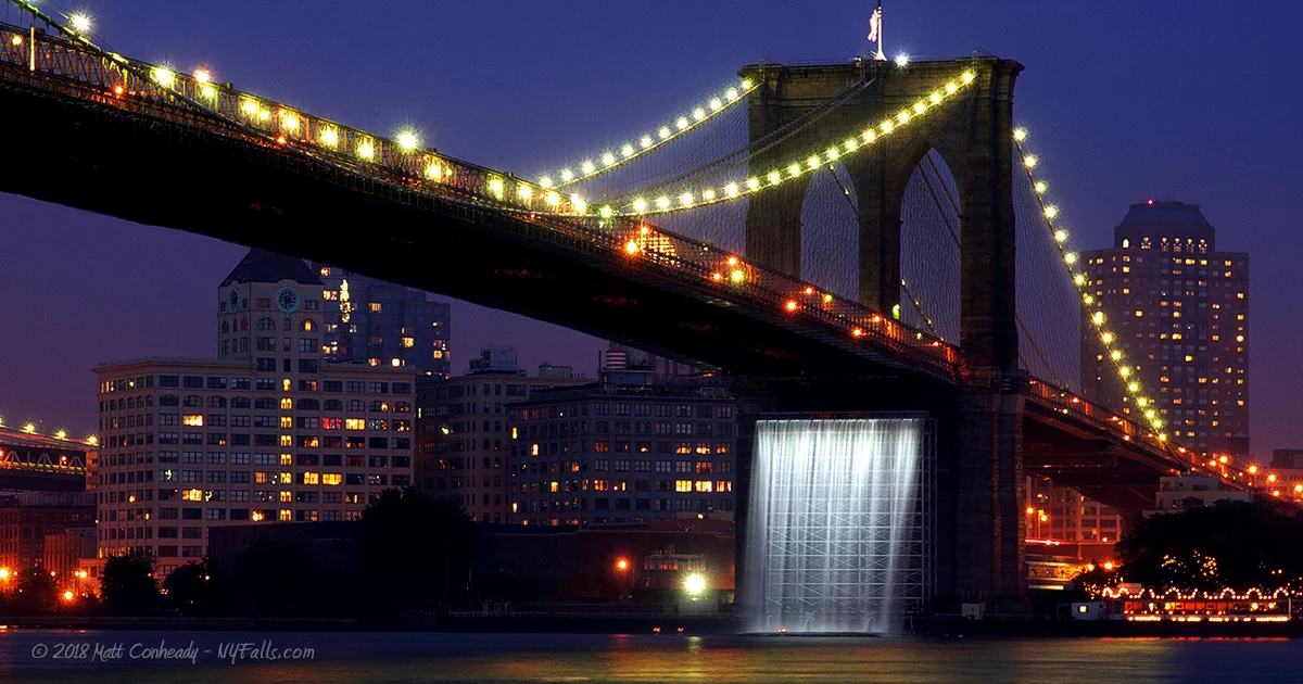 The Brooklyn Bridge at night with waterfall underneath it.