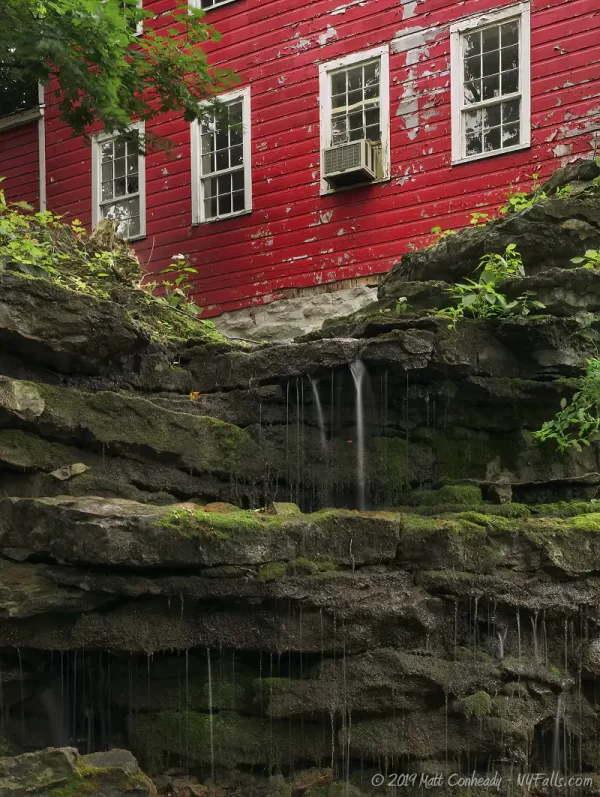 A view of the old red mill, which used to be a cider mill near the back of Glen Park. In the foreground is a cliff leading into an old mill race.