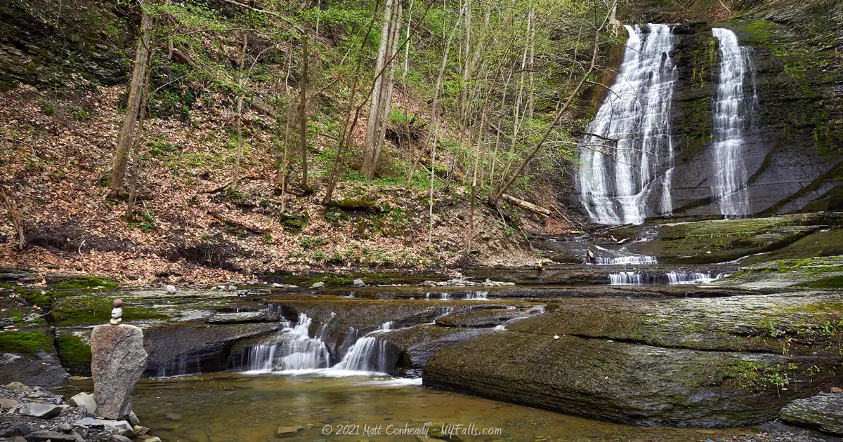 Lick Brook Falls at Sweedler and Thayer Preserves. On the left is small cairn left by a visitor. The waterfall's flow is low, exposing the mossy face of the falls.