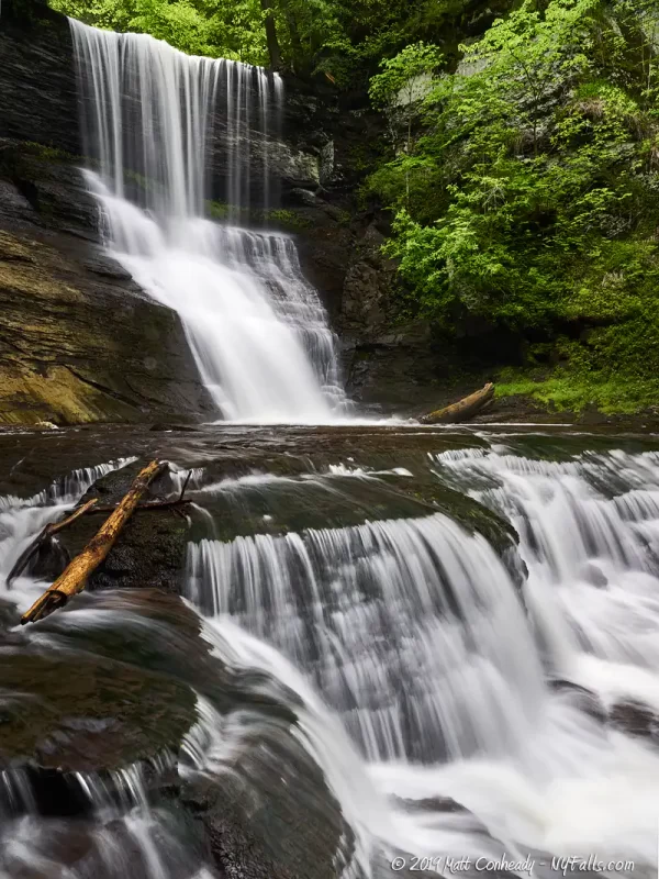 A tall view of lower Carpenter Falls, showing a small overhanging drop then a series of 2 cascades, the bottom one coming towards the camera.