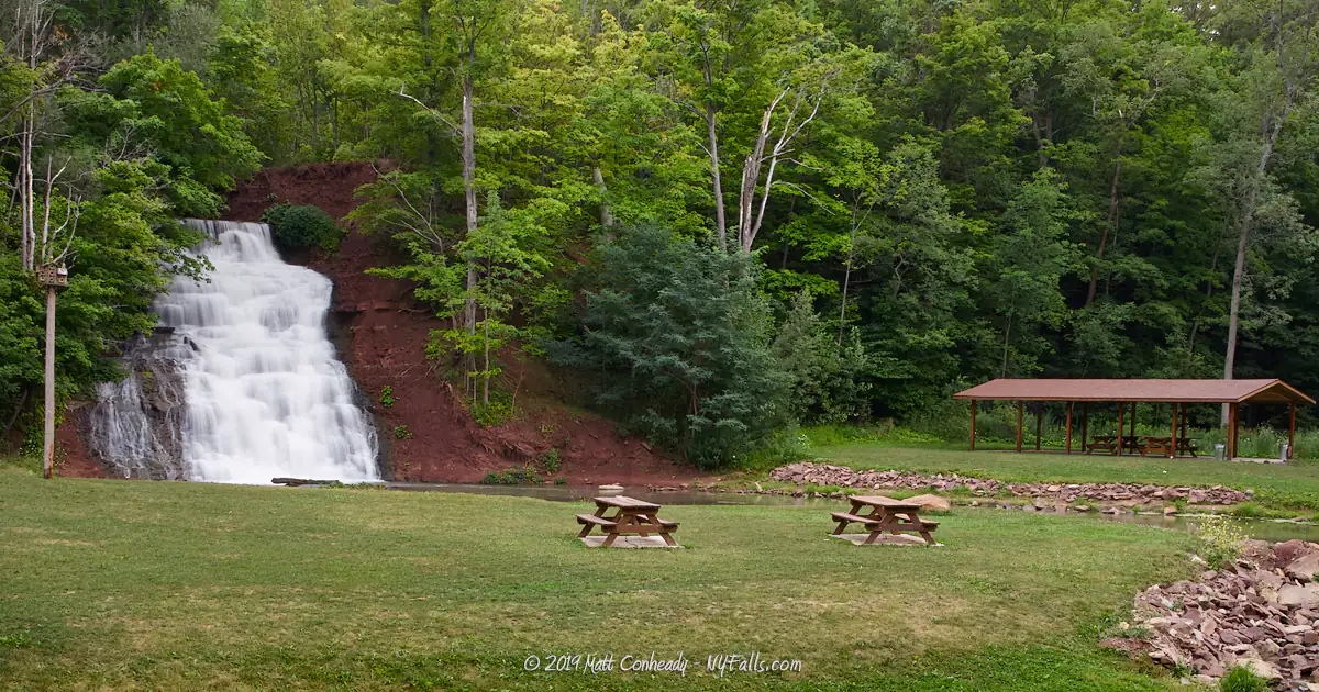 A view of Holley Canal Park showing the falls, picnic tables and a shelter