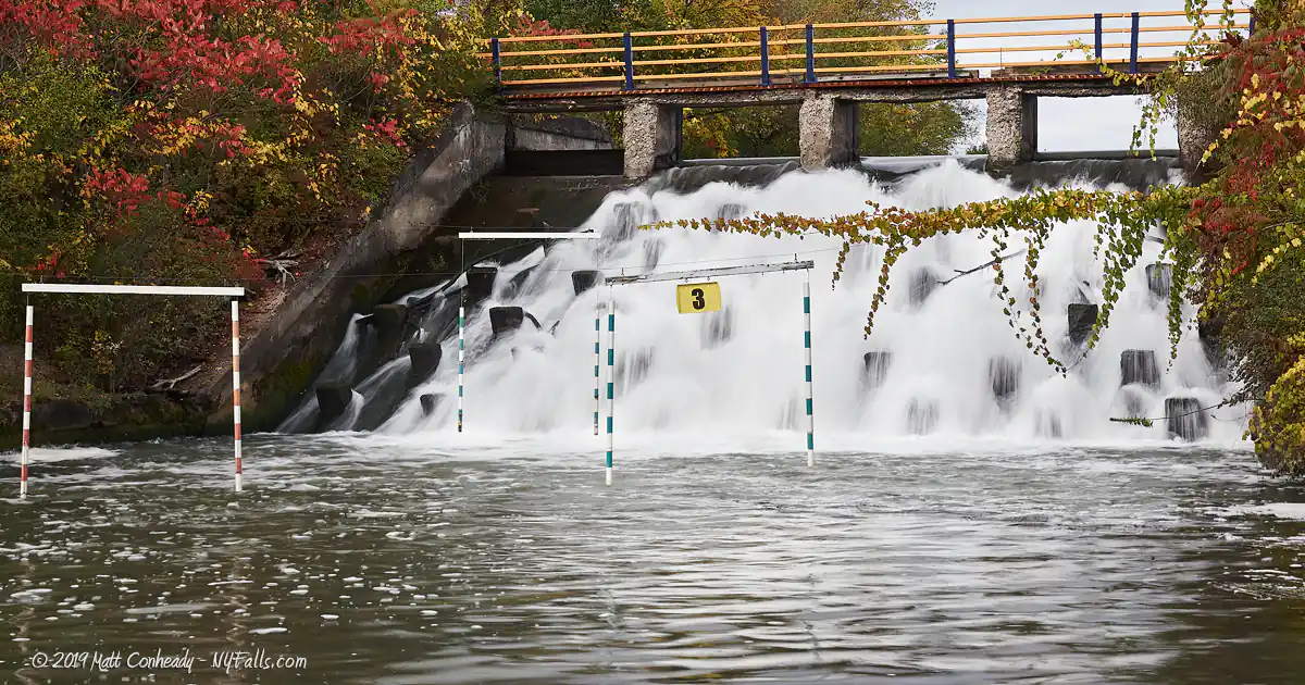 The waterfall at Lock 32 with canoe slaloms in front of it. Vines are growing across the rope used to hang the saloms.