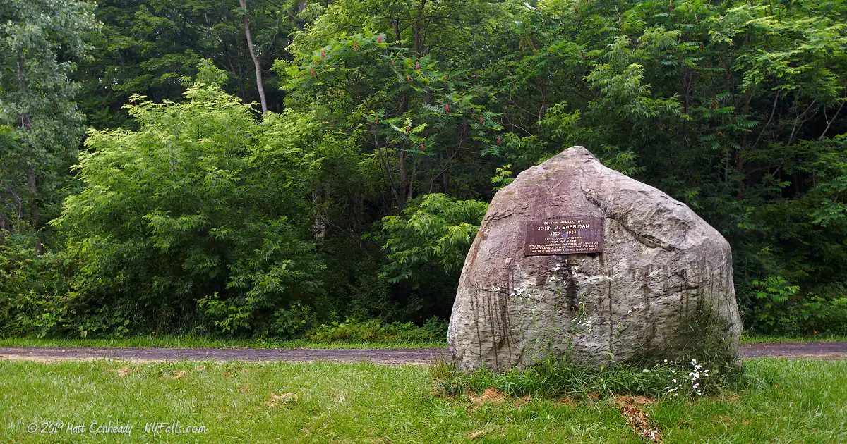 A large boulder along the Keuka Outlet Trail that has a plague memorializing John Sheridan, who helped establish the trail.