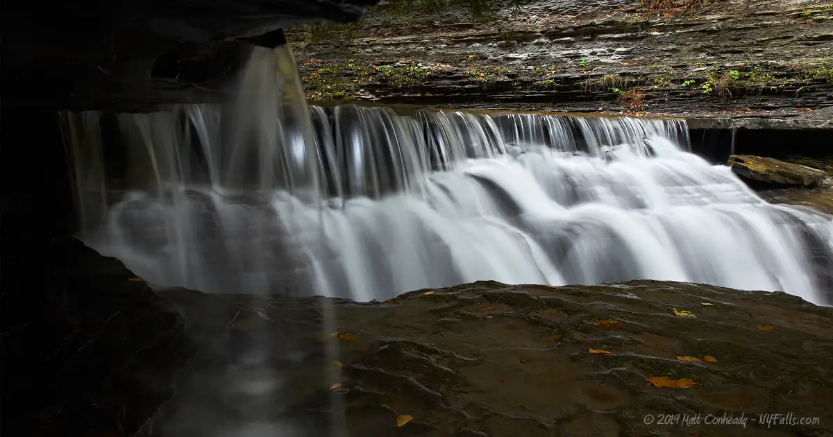 A shot of a small waterfall taken from behind the falls.