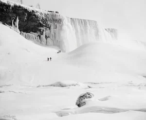 tourists walking along an ice bridge below Niagara Falls (c.1900)