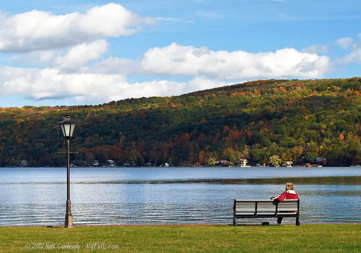 Someone sits on a bench at Depot Park in Hammondsport and enjoys the autumn view of Keuka Lake