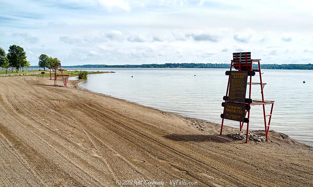 An empty swimming beach with life guard chairs on Cayuga Lake