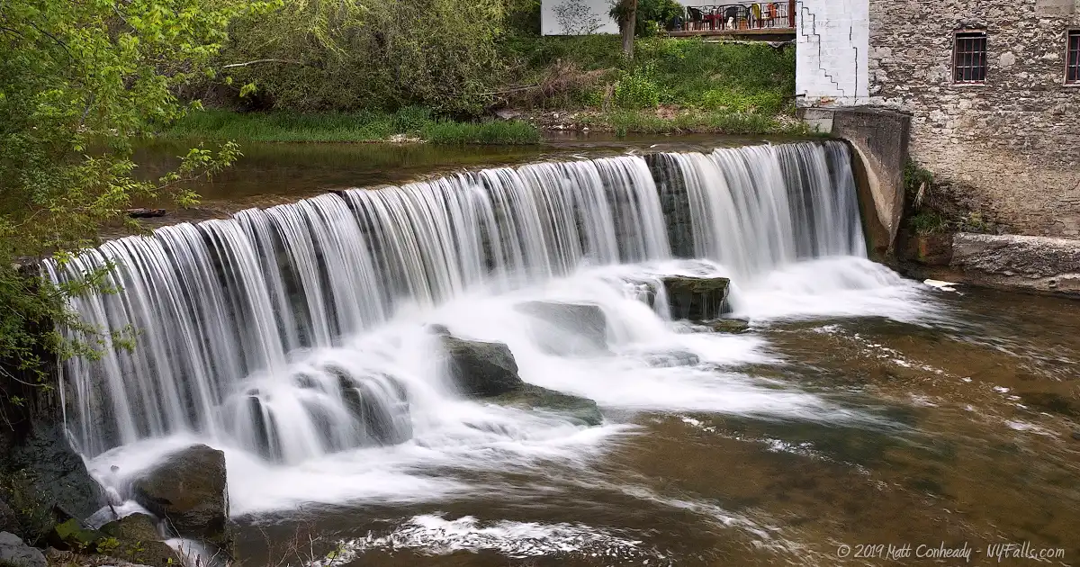 Old Mill Falls on Flint Creek in Phelps with the exterior wall of the mill visible in the top right of the frame.