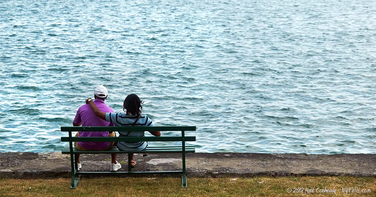 A couple sits along the shoreline of Skaneateles Lake