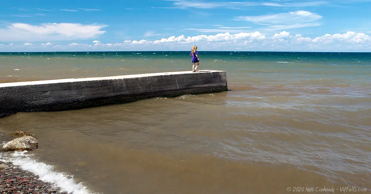 A child walks along the pier on Lake Ontario at Barker Park