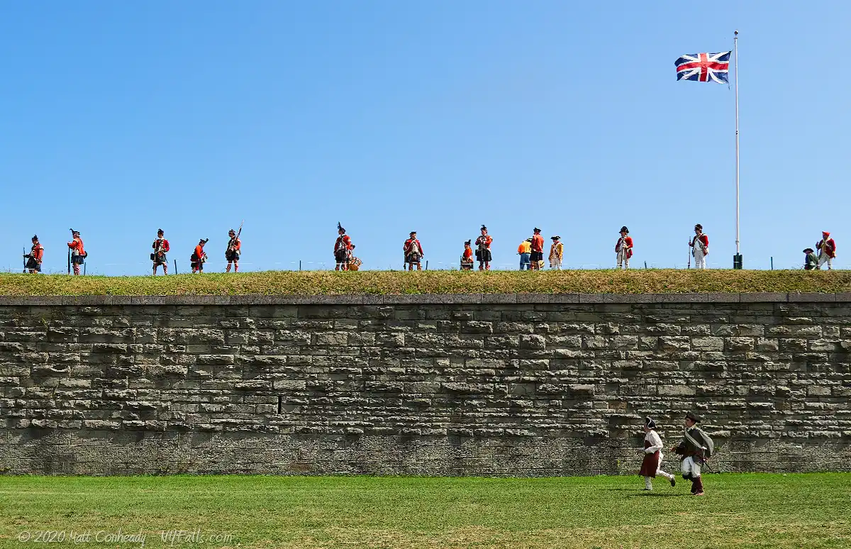 A scene from battle reenactment at Fort Ontario State Historic Site, where soldiers are standing guard above the fort walls.