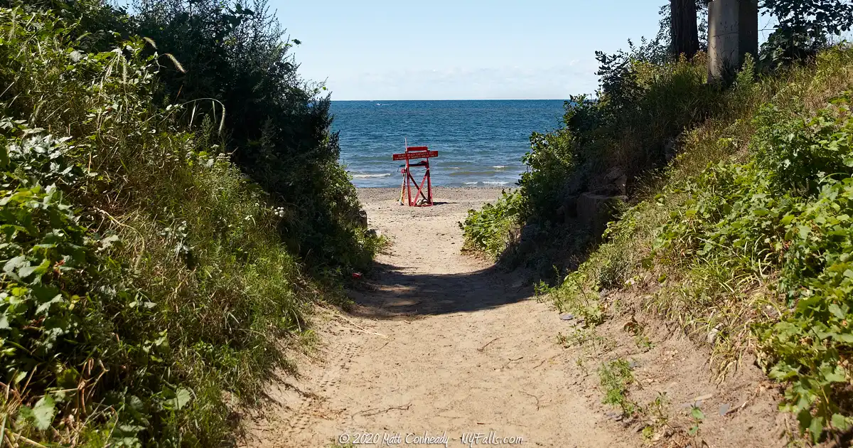 A path between two hills leads to Wendt Beach. A lifeguard chair is seen on the shore.