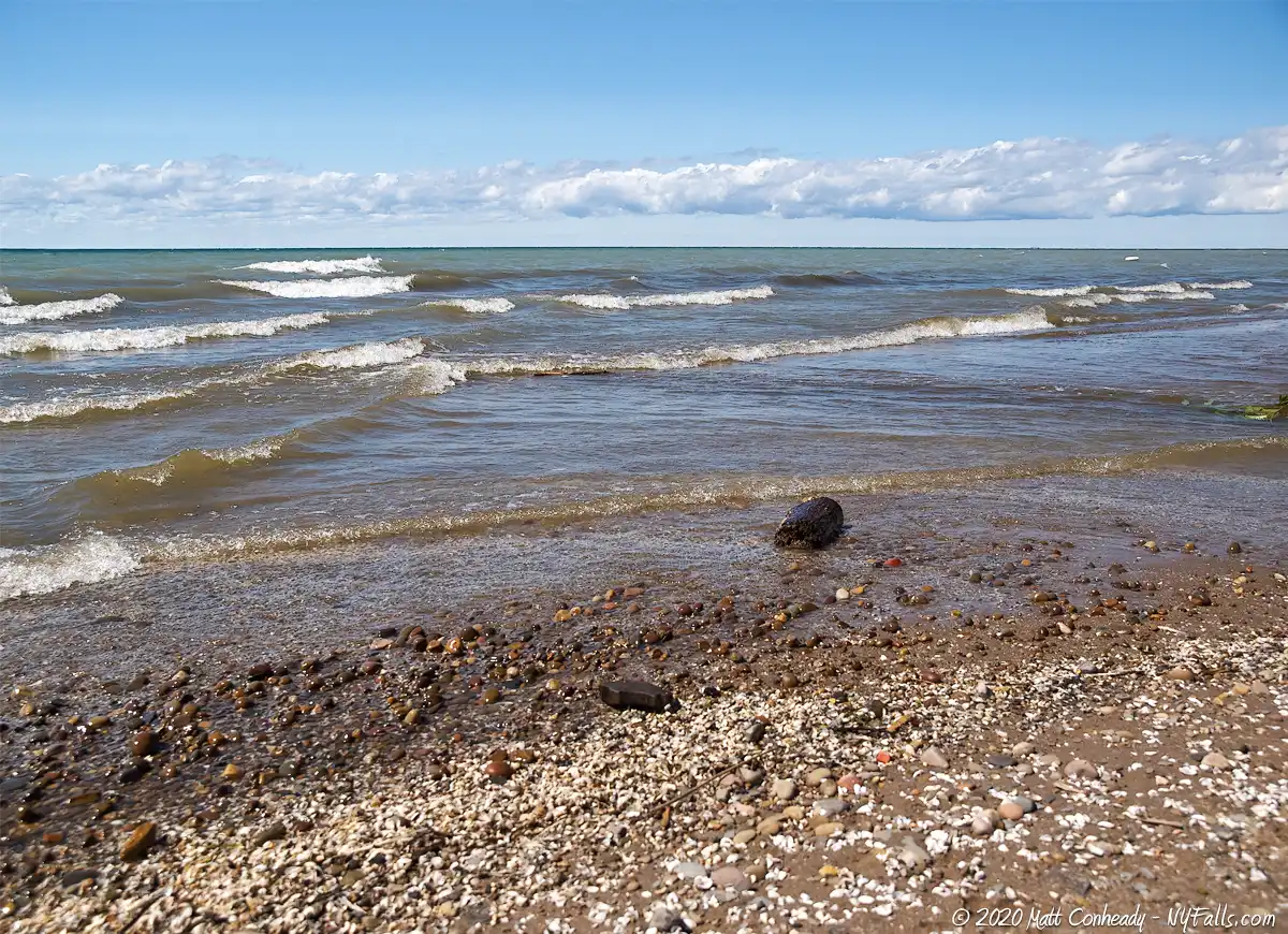 Uneven rows of small waves along Lake Erie Beach Park's shore on a sunny summer day.