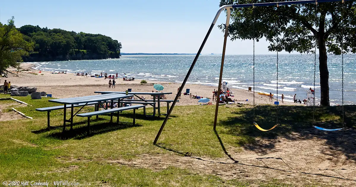 Looking past a swing set and picnic table at the swimming beach at Lake Erie Beach Park