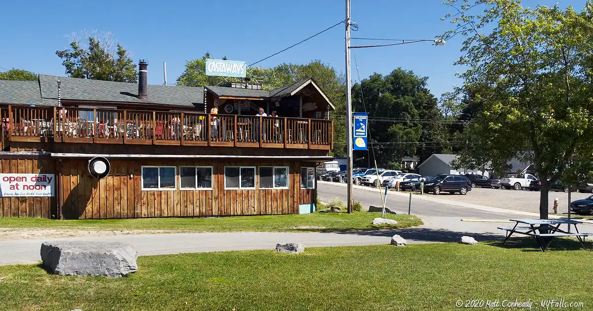 A two story restaurant with patio located adjacent to Lake Erie Beach Park
