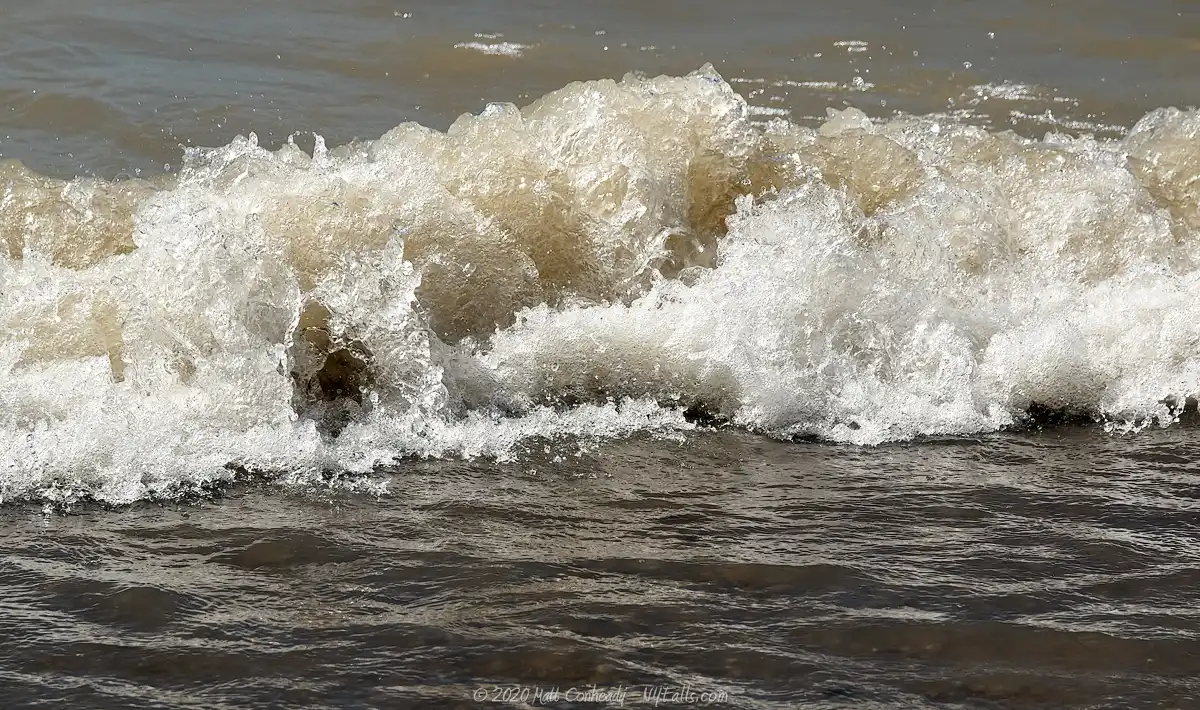 A small wave crashing on the beach at Evangola State Park.