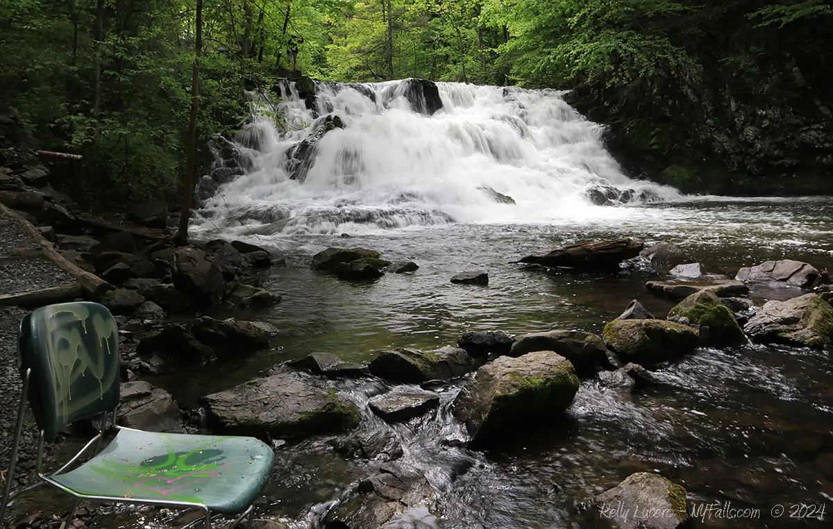 Wide angle view of Zabriskie's Waterfall showing a vintage plastic chair and rocks in the foreground.