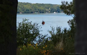 A fisherman in a boat with 4 fishing poles and an electronic device